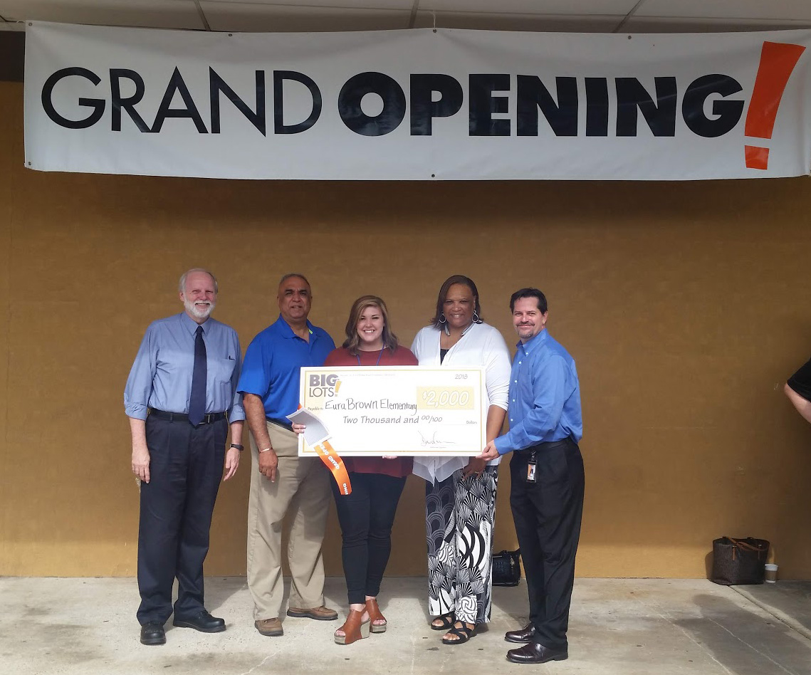 Group under Grand Opening sign with oversized check for $2,000