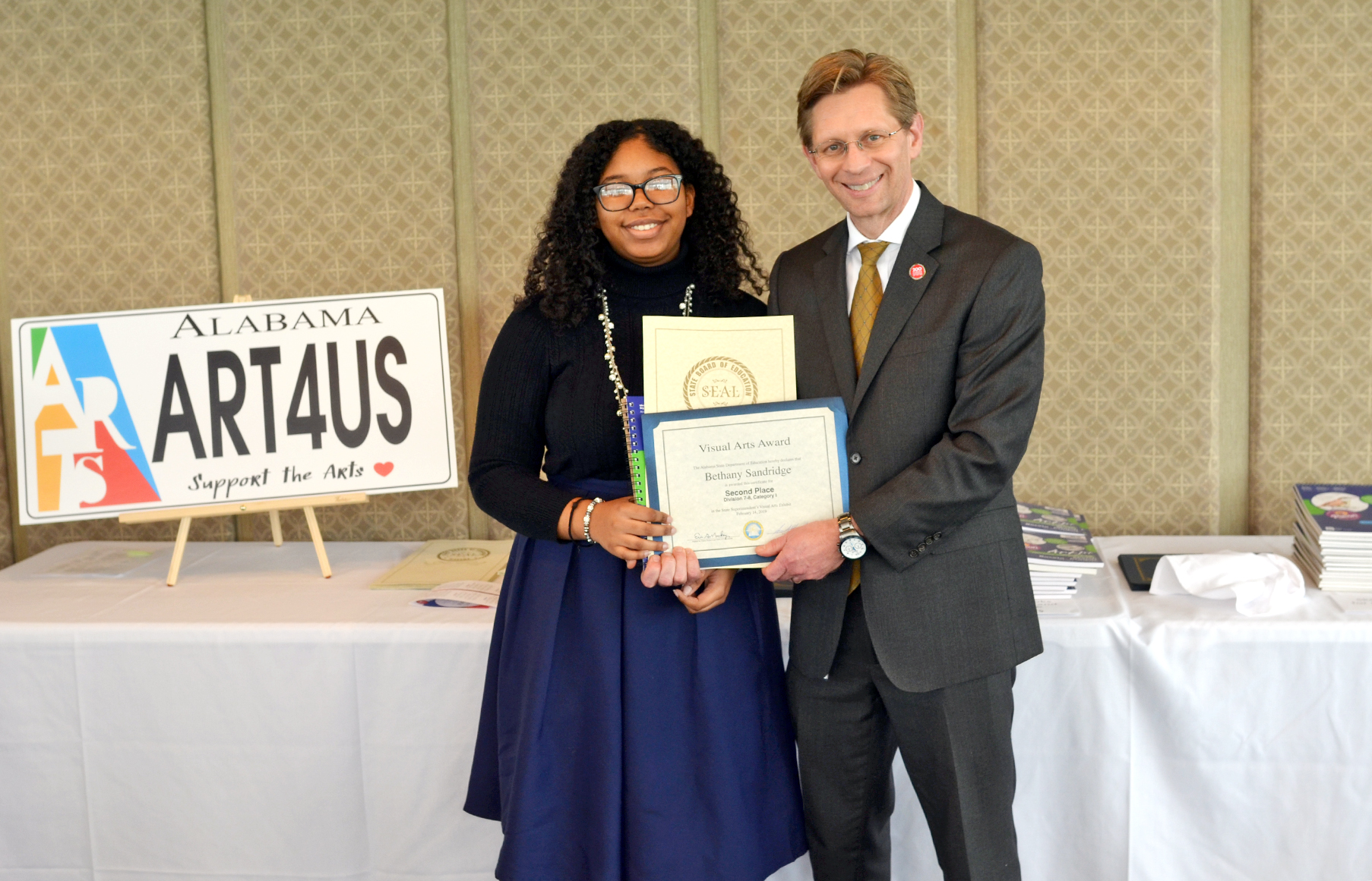 Student receiving award with State Superintendent of Education Eric Mackey