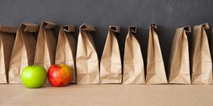 Row of lunch paper sacks with apples